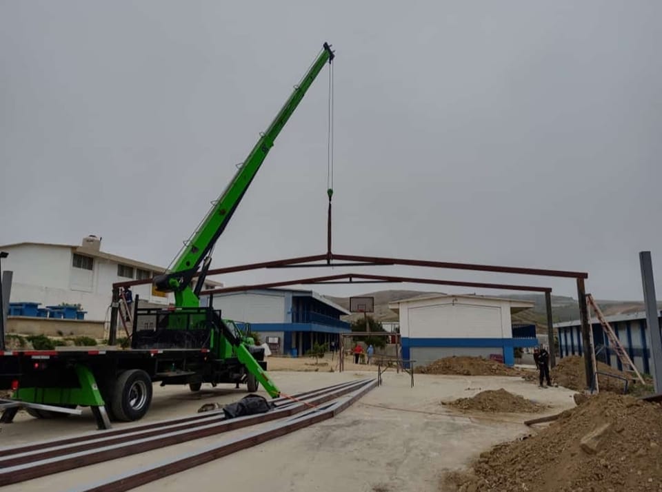 Grúa industrial realizando izaje de estructura metálica en obra